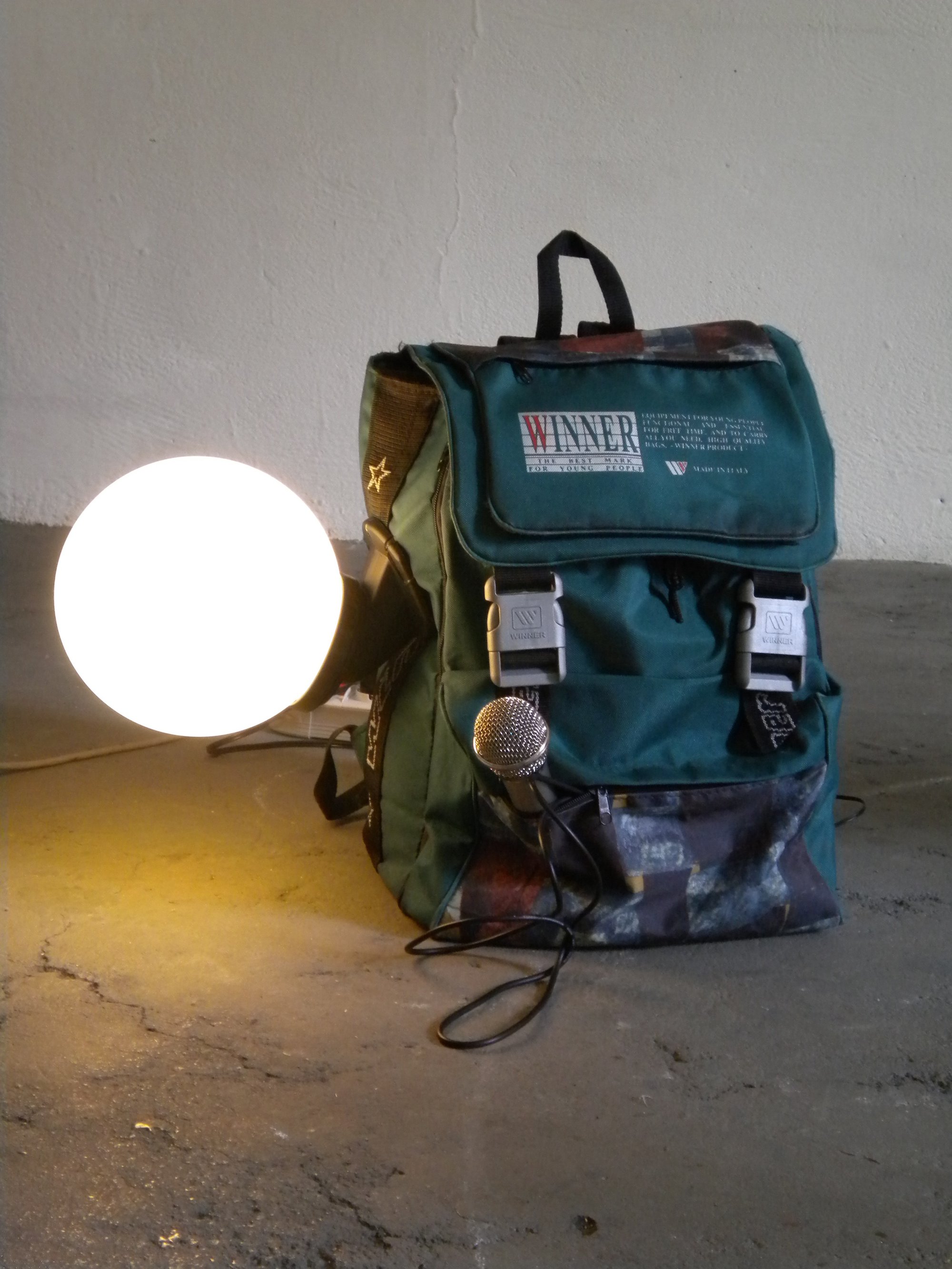 Liliana Moro, Maria, white globe lamp with lighted bulb, microphone, backpack with loudspeaker inside, soundtrack: operas sung by Maria Callas, dimensions variable, 2012