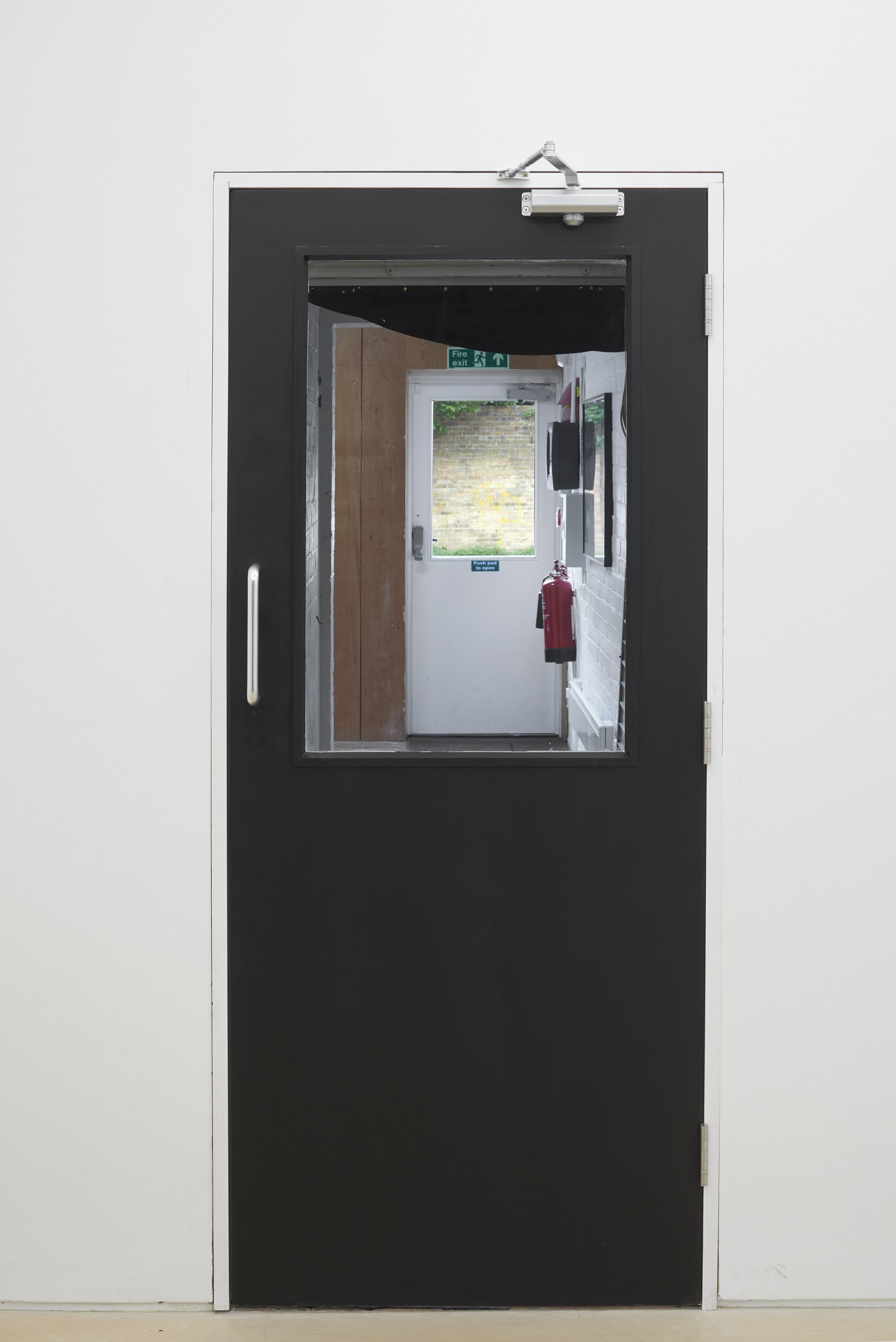 Iris Touliatou, KNOCK-OFF SECURITY RETROFIT, new doorway, Part Glazed Fire Door Complete with frame, glass, ironmongery and decorations in black Satinwood, fabricated and installed by JH Contract Services (Ltd), 198 x 89 x 98 x 83 cm, 2023Installation view, Iris Touliatou, Outfits, Peer, London, 2023.