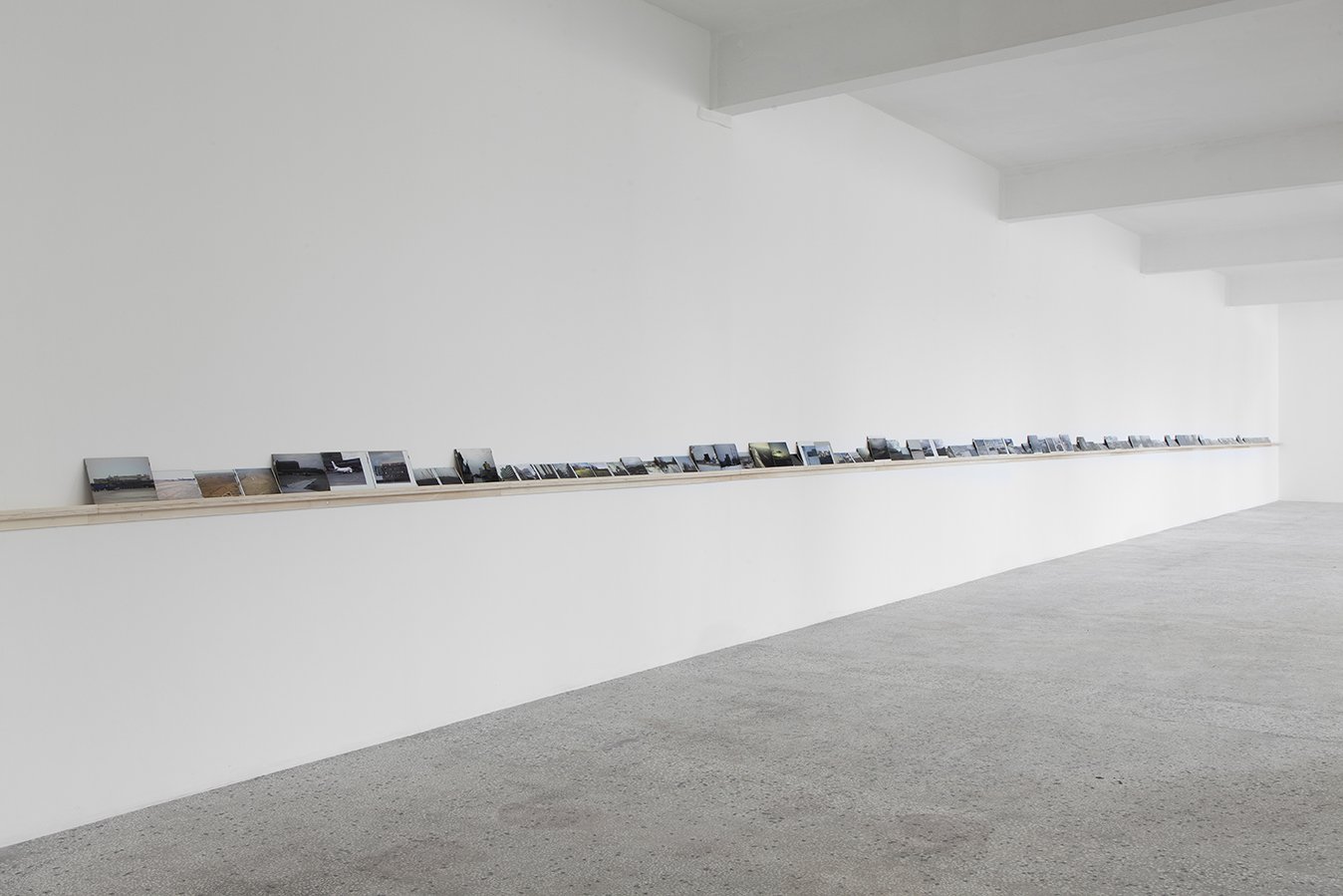 Vangelis Vlahos, Is There Any Oversight On Ocalan?, 119 photographs (framed), dimensions variable: biggest 24 x 30 cm (9 1/2 x 11 3/4 in) smallest 10 x 15 cm (4 x 5 7/8 in) on a wall mounted shelf 23 m long (905 1/2 in), 2009 – 2011