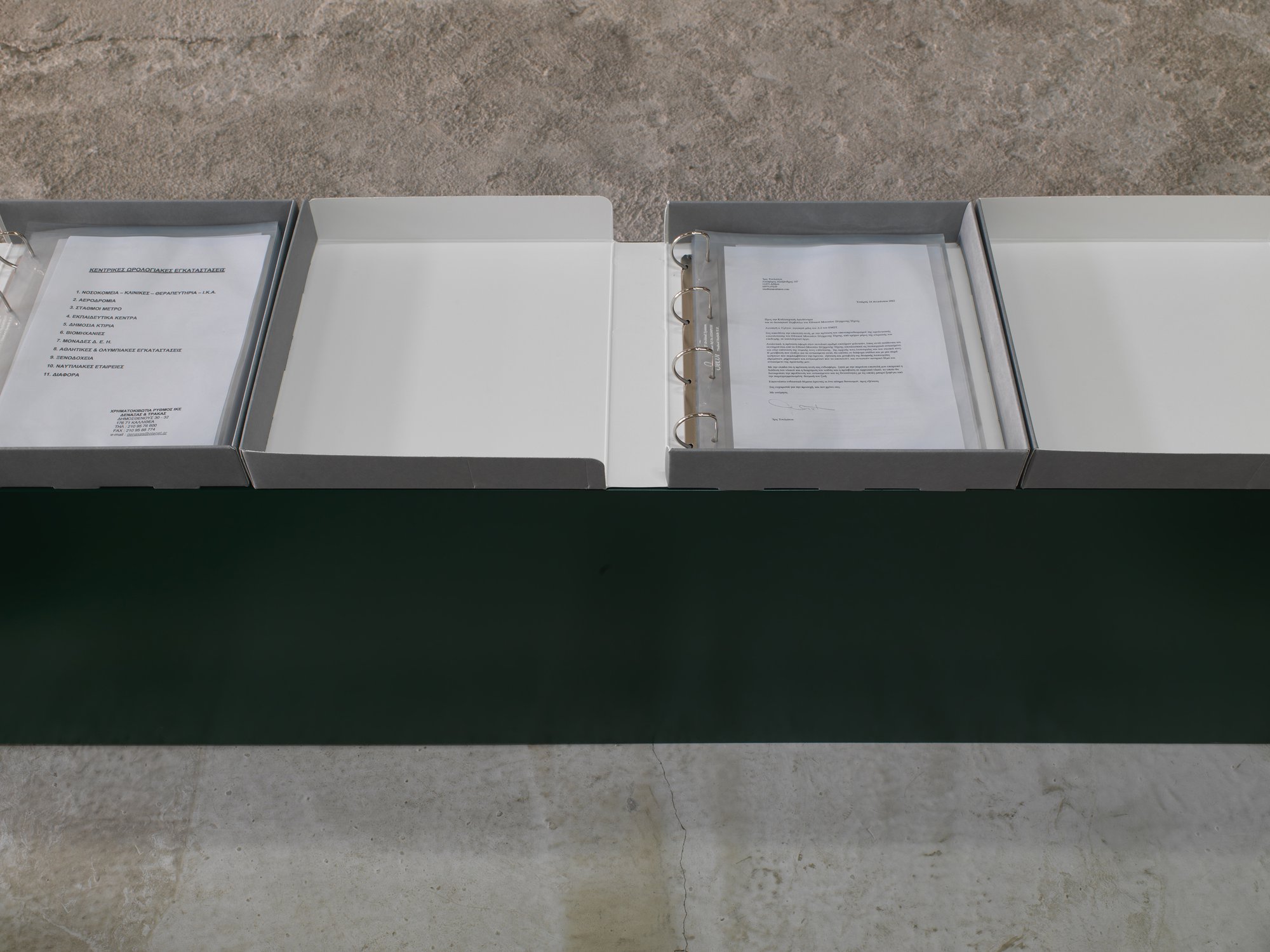 Iris Touliatou, mother material, four archival grey filing dossiers: 32,5 x 31 x 5,5 cm each (12 3/4 x 12 1/4 x 2 1/8 in each), A4 archival transparencies, official documents, correspodance, requests, operation manuals, lacquered MDF pedestal in Rodeo green (RAL 6005), in progress, 2022