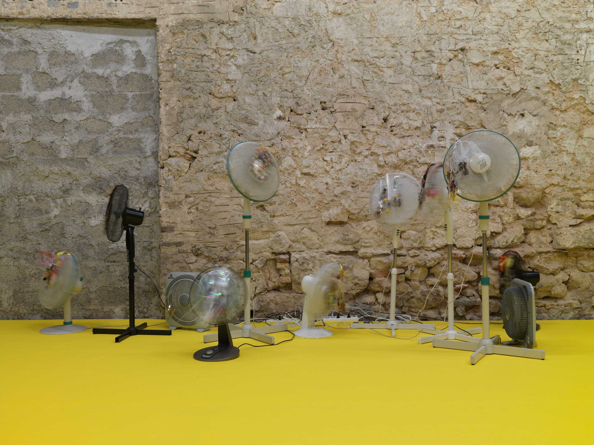 Iris Touliatou, EMOTIONAL INFINITY (THE SOUND OF THEM COMING BACK AMPLIFIED AND LOOPED), oscillating fans, duplicated house keys, pre owned keychains, string, ribbons, gift bows, wire, timers, multiplugs, outlets, dimensions variable, 2022.Installation view, anabasis*, Rodeo, Piraeus, 2022.