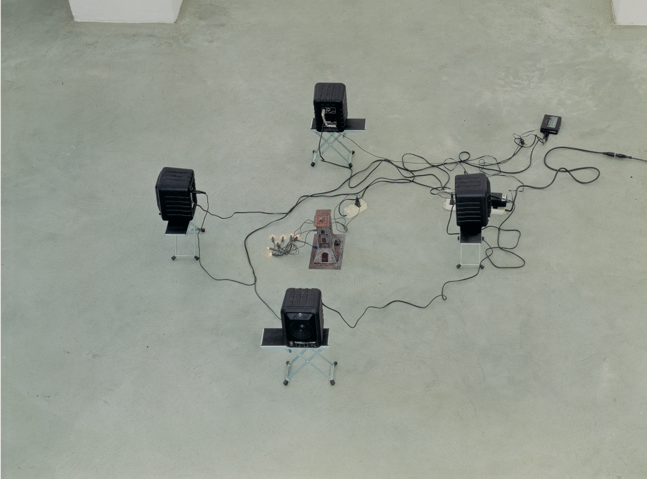 Liliana Moro, Nessuno, 4 acoustic speakers, guitar stand, paper construction, flashing lights, speaker with recording of the artist reading the text “happy days” by Samuel Beckett, dimensions variable, 1993. Installation view, Liliana Moro, Nessuno, Emi Fontana Gallery, Milan, 1993